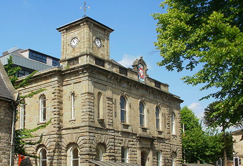 A town hall building cropped to focus on the crest and clock tower.)